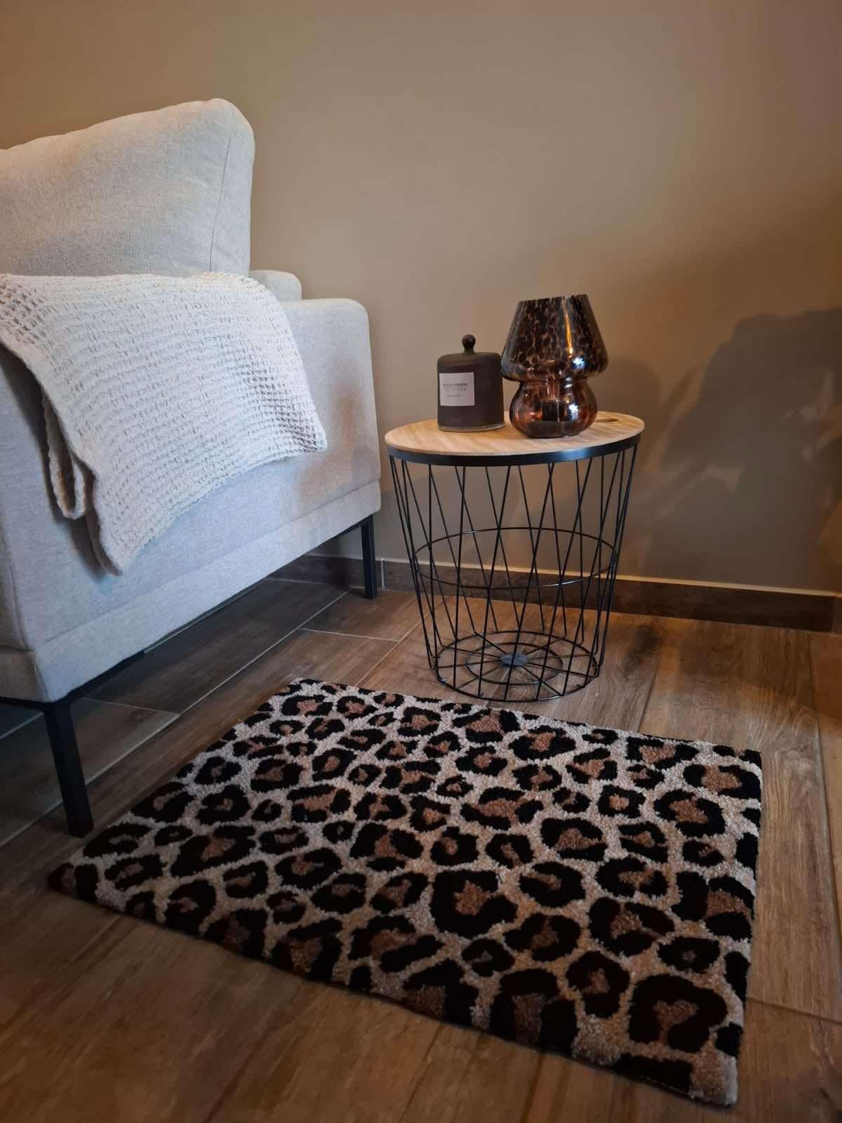 Tapis en laine tufté main motif léopard, posé au pied d’un fauteuil